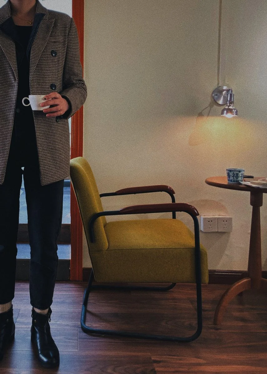 Paint By Numbers | Nantong - Person Holding White Ceramic Teacup Standing Near Vacant Beige Padded Armchair